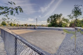 an empty parking lot with a chain link fence and a bench