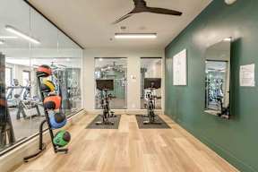 A gym with a variety of equipment including a stationary bike and a rowing machine.