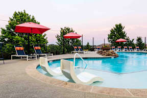 A pool with a white diving board and red umbrellas.