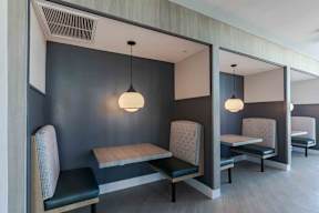 two tables and two chairs in a room with a wall and two lamps