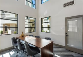 a meeting room with a large wooden table and black chairs