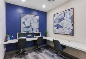 three computers in a room with a blue accent wall