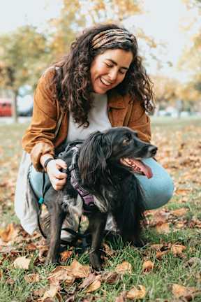 A woman is playing with her dog in a park.