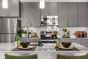 A modern kitchen with a stainless steel refrigerator and a center island with two bowls on top.