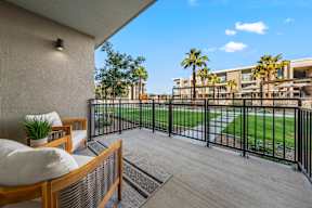 A balcony with a wooden bench and a black railing.