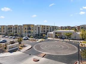 A roundabout in front of apartment buildings with cars parked on the side.