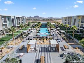 A pool surrounded by palm trees and apartment buildings.