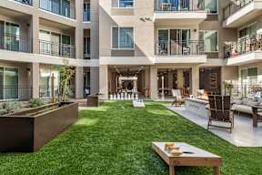 A modern courtyard with a wooden bench and a fireplace.
