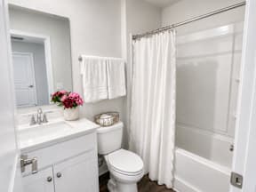 A white bathroom with a toilet, sink, and shower.