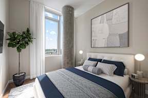 A bedroom with a large bed and a potted plant.
