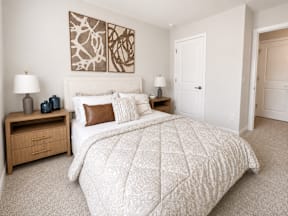 A bedroom with a large bed and two nightstands.