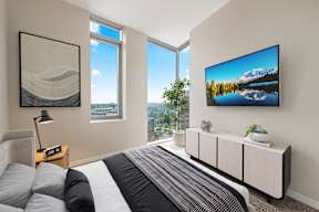 A bedroom with a large bed and a TV mounted on the wall.