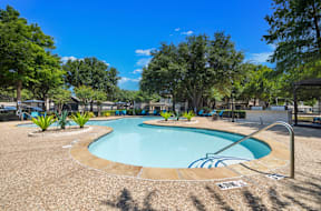 A large outdoor resort-style pool surrounded by trees and plants at Bardin Greene Arlington, TX apartments for rent.