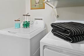 a white washer and dryer in a bathroom with a stack of black towels