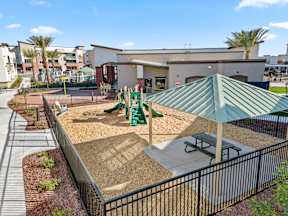 a playground with a picnic table and benches in front of a building