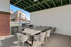 a patio with a table and chairs and a grill