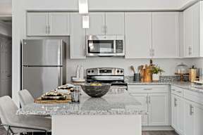 a kitchen with white cabinets and a marble counter top