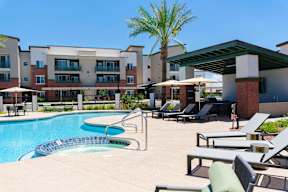 a swimming pool with chairs and umbrellas in front of an apartment building