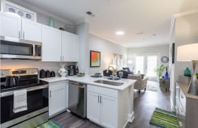 a kitchen and living room with white cabinets and stainless steel appliances