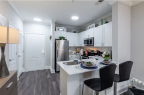 an open kitchen and dining area with stainless steel appliances and white cabinets