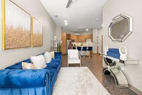A blue couch with white pillows sits in a room with a white rug.
