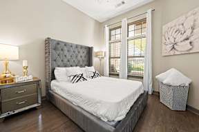 A bedroom with a large bed, a nightstand with a lamp, and a painting on the wall.