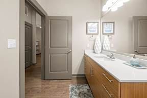 A bathroom with a white counter top and a wooden cabinet.