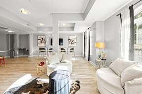 A living room with white furniture and a cowhide rug.