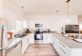 A modern kitchen with white cabinets and a wooden floor.