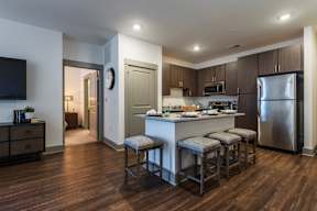 A kitchen with a bar stool and a refrigerator.