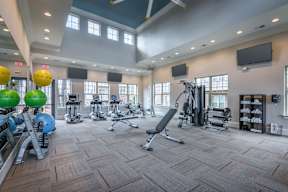 A gym with a variety of equipment including treadmills, weights, and exercise balls.