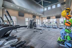 A gym with a variety of exercise equipment including treadmills, weights, and exercise bikes.