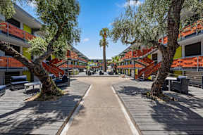 a courtyard with trees and benches and buildings in the background