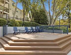 A wooden deck with blue chairs and a table.