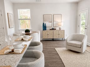 A dining room with a table set for two and a grey sofa.