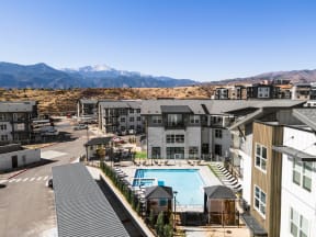 an aerial view of an apartment complex with a pool and mountains in the background
