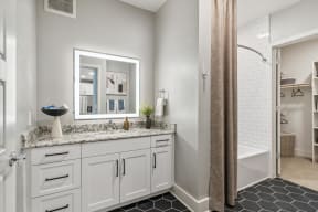 a bathroom with white cabinets and a shower and a sink