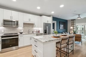 a kitchen with white cabinets and a marble counter top