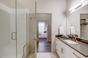 Two bedroom model bathroom with glass enclosed shower and large sink vanity