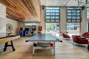 A ping pong table is in the middle of a room with a wooden ceiling.