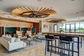 A modern living room with a wooden ceiling fan and a bar area.