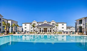 A large swimming pool in front of a building with a clear blue sky above.