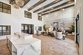 A modern kitchen with a marble island and a chandelier.