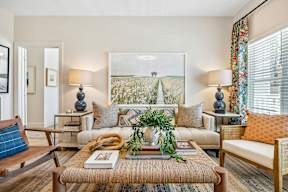 A living room with a sofa, a table with a plant, and a painting on the wall.