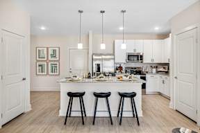 A kitchen with a white island and black stools.