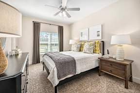 A bedroom with a bed, nightstand, and a ceiling fan.
