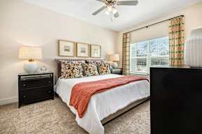 A bedroom with a bed, nightstand, and a ceiling fan.