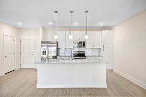 A modern kitchen with a white countertop and stainless steel appliances.