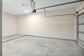 A large empty room with a garage door on the side.