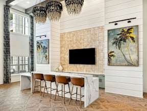 A modern kitchen with a bar area and a painting of a palm tree on the wall.